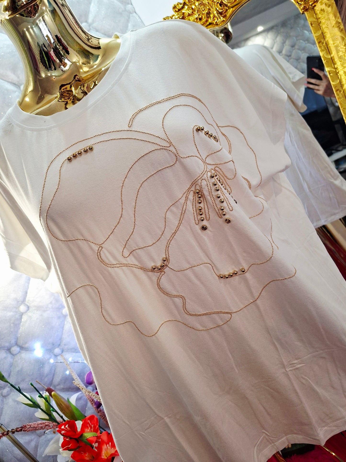 Rozžiarte svoj outfit s týmto nádherným bielym tričkom, ktoré je zdobené oslnivými zlatými zirkónmi