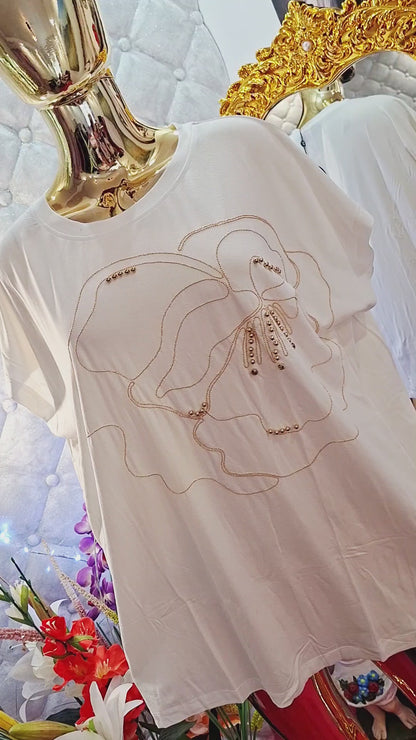Rozžiarte svoj outfit s týmto nádherným bielym tričkom, ktoré je zdobené oslnivými zlatými zirkónmi